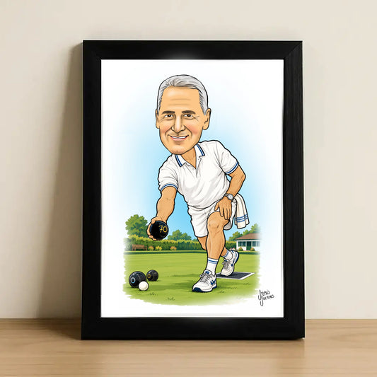 A framed caricature art print of a man bowling on a lawn, displayed on a light wooden surface against a neutral beige wall. The print features a white background with a blue sky gradient, showing the man in a white polo shirt and shorts holding a bowling ball, enclosed in a simple black frame.