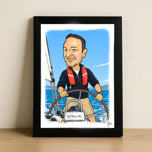 A framed caricature portrait print of a man steering a sailboat on the water, shown leaning against a beige wall on a light wood surface. The artwork is inside a black frame with a white mat and features a blue sky and sea background.